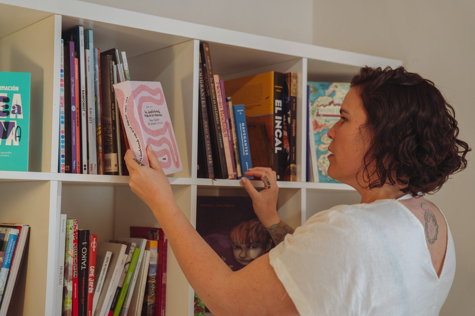 Ío Bru eligiendo un libro ilustrado en su estantería