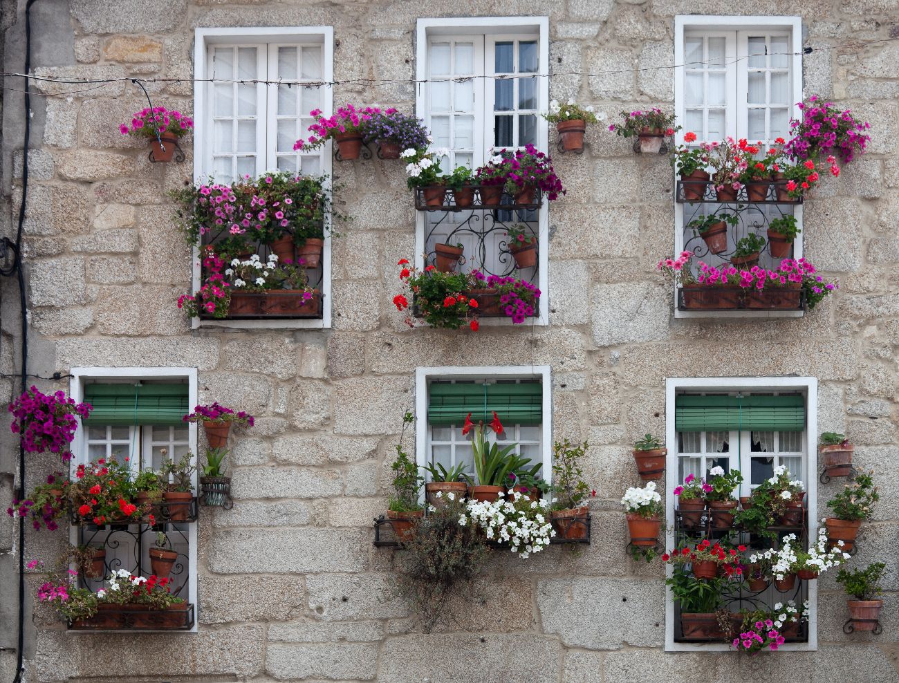 Fachada de granito con galerías y flores en Ribadavia